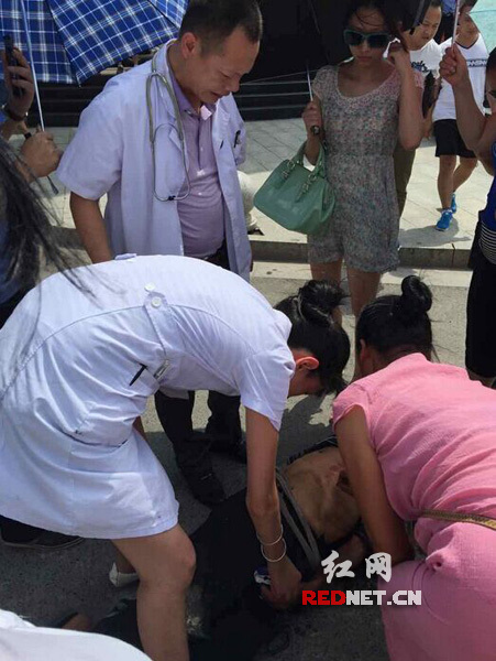 老人中暑晕倒在马路中间 邵阳姑娘为其撑伞遮阳