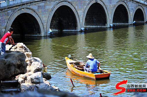 小朋友看到刚扔进迎泽公园湖里的垃圾被清洁员划船捞走 本网记者