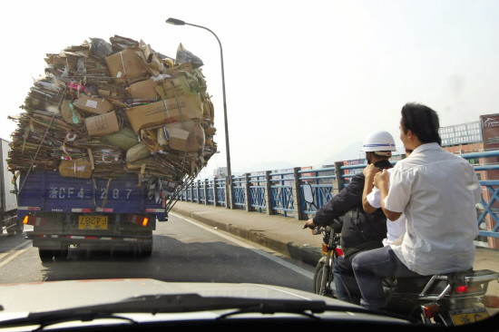 一车纸板箱单边倒超载摩托车擦肩过