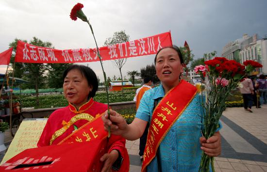 張娟娟(右一)和志願者一起在咸陽市人民廣場上義賣鮮花,幫助地震災區.