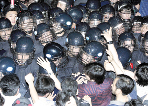右图 6月26日,在韩国首都首尔,防暴警察与抗议政府恢复进口美国牛肉的