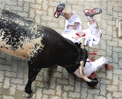 12日,在西班牙潘普洛纳奔牛节上,一名男子被公牛顶倒,伤势严重.(图)