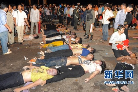 11月23日,在柬埔寨金边,人们站在踩踏事件遇难者遗体旁.新华社/法新