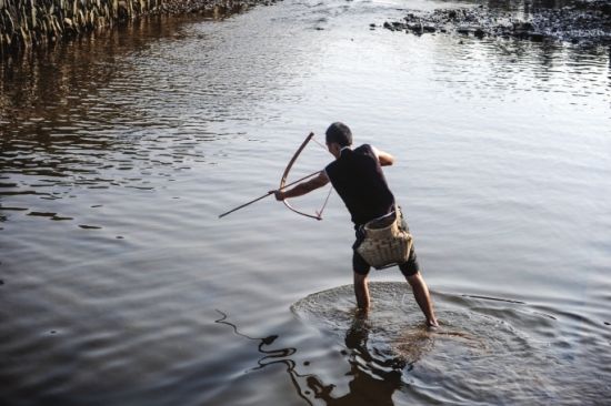 村民正在用弓箭射鱼.