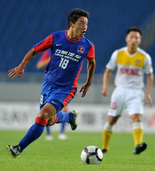 7月28日,重庆力帆队球员胡伟(左)带球进攻.